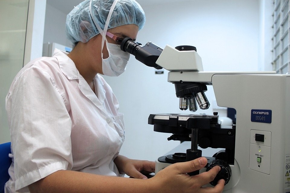 Lab assistant studying drug matter under a microscope